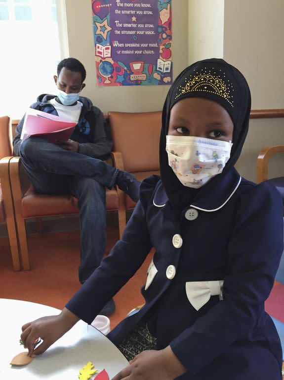 Amira Hassan plays in the waiting room at Children's Minnesota  while her dad, Mohamud Hassan, fills out paperwork.