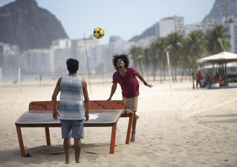 Dos hombres juegan teqball en medio de la pandemia de coronavirus en la playa de Copacabana, Río de Janeiro, Brasil, el jueves 2 de julio de 2020. Teqball es un deporte que se juega sobre una mesa cóncava y que combina los elementos del fútbol y el tenis de mesa. Las autoridades de Río de Janeiro han comenzado a levantar las restricciones de la ciudad en medio de una creciente pandemia de COVID-19. (AP Foto/Silvia Izquierdo)