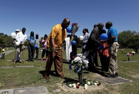 Gary Butts, family friend of the late Walter Scott, lays a rose at the gravesite as relatives and friends gathered to remember Scott, at Live Oak Memorial Gardens in Charleston, South Carolina, April 4, 2016. REUTERS/Randal Hill