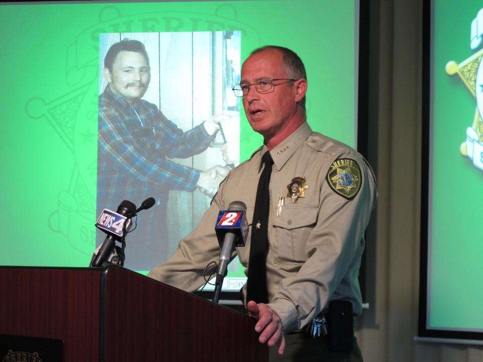 Storey County Sheriff Gerald Antinoro speaks to reporters at Washoe County sheriff's headquarters in Reno, Nev., Thursday, May 1, 2014, about the opening of an investigation into the apparent 1980 homicide of George Benson Webster of Sun Valley, who is pictured in the background. The highly decorated Vietnam veteran had been missing since then. His remains were found last summer in a septic tank at a home on the edge of the historic Comstock mining town of Virginia City about 20 miles from Reno. Detectives traced his identity with the help of a partial serial number on a medallion with the remains. (AP Photo/Scott Sonner)