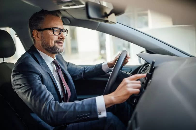 Mature man behind the steering wheel of a car using mobile phone