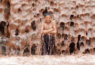 <p>An Afghan boy cools off under a muddy waterfall on the outskirts of Jalalabad province, Afghanistan May 16, 2017. (Photo: Parwiz/Reuters) </p>