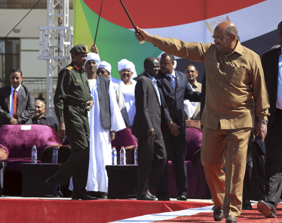 FILE - In this Jan. 9, 2019 file photo, Sudanese President Omar al-Bashir greets his supporters at a rally in Khartoum, Sudan. Three months after Sudanese protesters rose up against al-Bashir, the longtime autocrat has bound himself more tightly to the military and refused to bow to their demands. Al-Bashir has remained in power through three decades of war and sanctions, the secession of Sudan's oil-rich south in 2011 and an international arrest warrant for genocide and war crimes linked to the Darfur conflict. (AP Photo/Mahmoud Hjaj, File)
