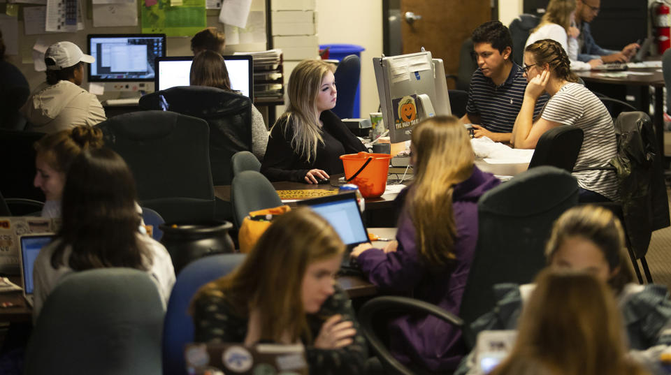 This Oct. 30, 2019 photo shows Editor-in-Chief Maddy Arrowood, background center, Editorial Managing Editor Marco Quiroz-Gutierrez, background second from right, and City & State Editor Anna Pogarcic, background right, with other staffers at the editorial office of The Daily Tar Heel, the independent student newspaper of the University of North Carolina in Chapel Hill, N.C. Thousands of young journalists train for the future on a dual track, in classrooms and in student-run newsrooms that are models for the places they hope to work someday. (Dustin Duong/The Daily Tar Heel via AP)