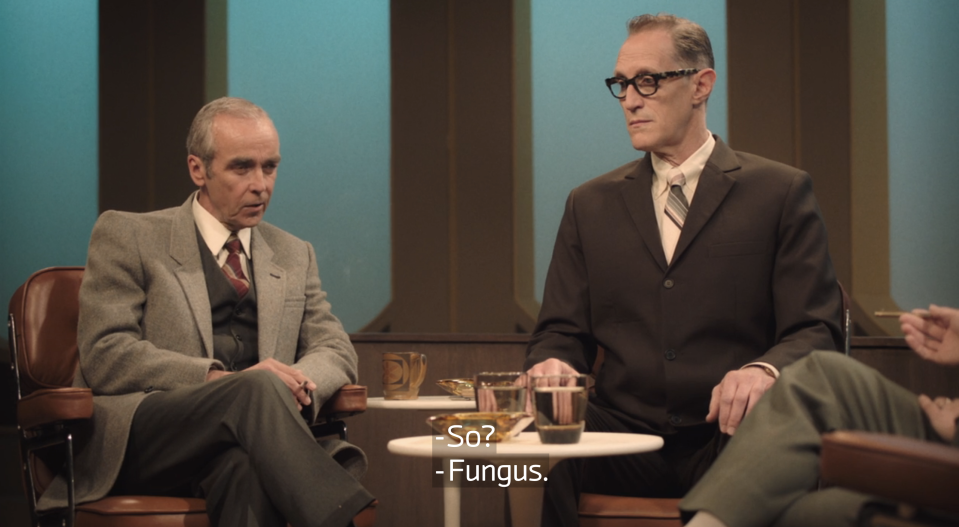 Two men sitting together on a TV interview show talking about fungus