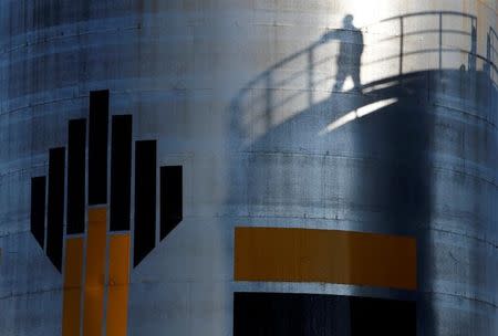 The shadow of a worker is seen besdide the logo of the Rosneft oil company at an oil field in Russia, August 4, 2016. REUTERS/Sergei Karpukhin/Files