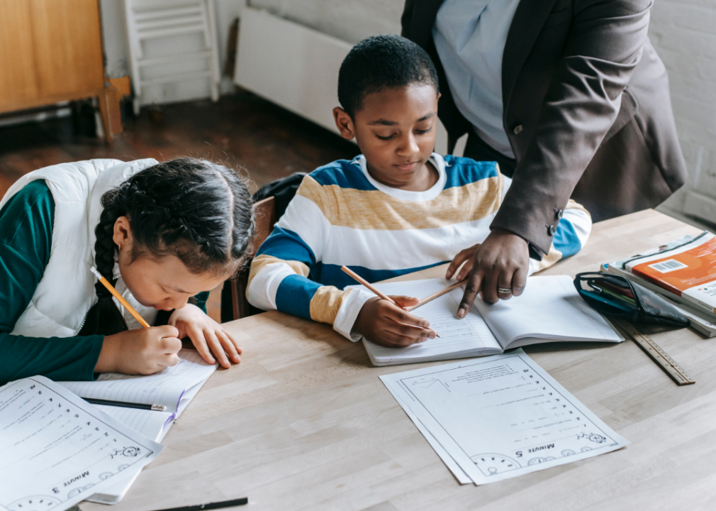 A tutor helping two young students.