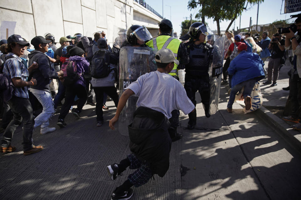 Migrants break past a line of police as they run toward the Chaparral border crossing in Tijuana, Mexico, Sunday, Nov. 25, 2018, near the San Ysidro entry point into the U.S. More than 5,000 migrants are camped in and around a sports complex in Tijuana after making their way through Mexico in recent weeks via caravan. (AP Photo/Ramon Espinosa)