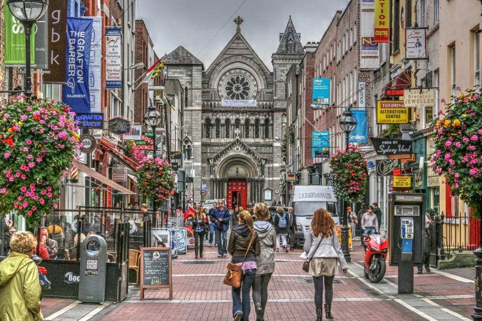 famous shopping area in dublin, ireland grafton street showing shoppers, shops and church
