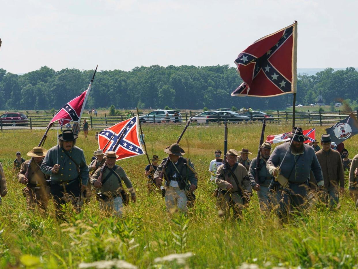 FILE - In this Friday, July 3, 2020, file photo, Civil War reenactors marching with Confederate battle flags during their reenactment of Pickett's Charge at Gettysburg National Military Park in Gettysburg, Pa. The banner, with its red field and blue X design, is the best known of the flags of the Confederacy, but the short-lived rebel nation also had other flags. (AP Photo/Carolyn Kaster, File)