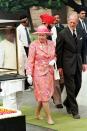 <p>The queen is dressed in a pink floral printed dress, matching blazer, and hat. Both she and Prince Philip removed their shoes, but kept on their socks, for a visit to the site of Gandhi's cremation in New Delhi, India. Walking barefoot on the grounds shows respect to the deceased. </p>