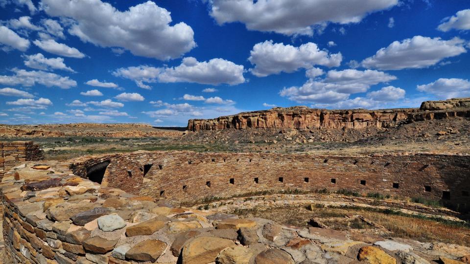 An old stone wall sits under a blue sky in Chaco Canyon in New Mexico