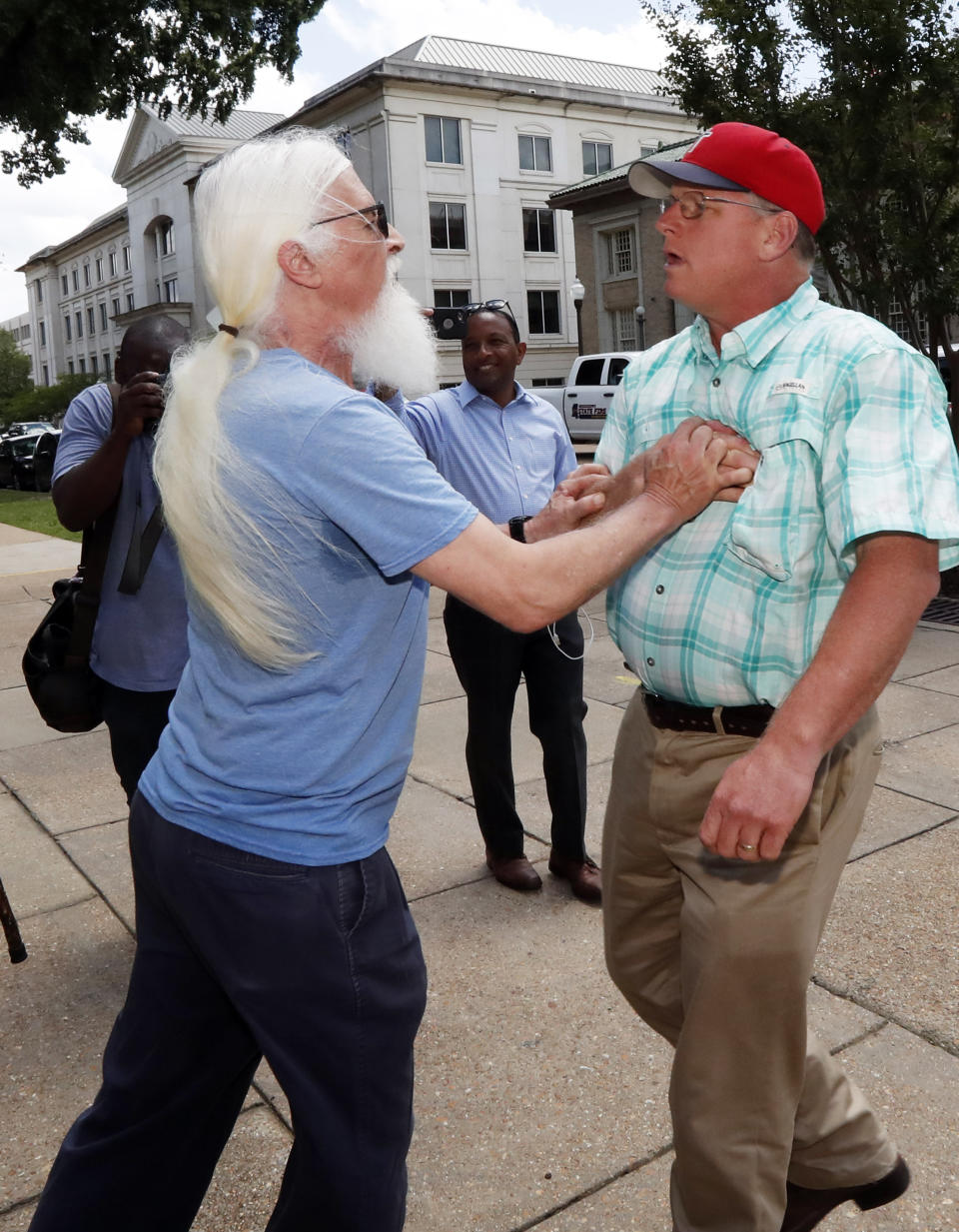 An abortion rights advocate who did not want to be identified detains Coleman Boyd, right, an anti-abortion supporter, as he tries to disrupt a gathering of rights advocates who gathered at the Capitol in Jackson, Miss., to voice their opposition to the state legislature passing a new law that prohibits most abortions once a fetal heartbeat can be detected, Tuesday, May 21, 2019. (AP Photo/Rogelio V. Solis)