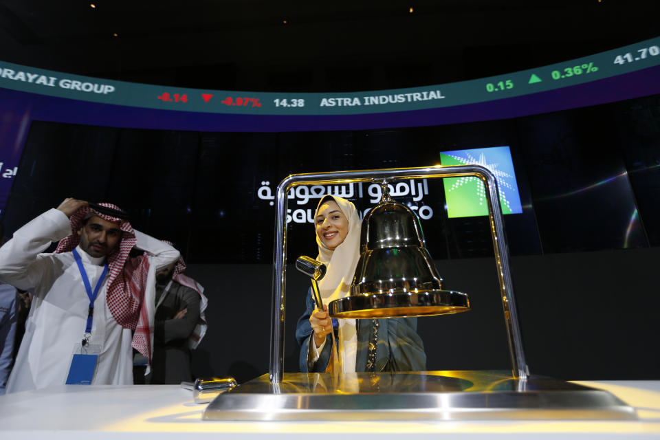 Saudi Arabia's state-owned oil company employee Sukaynah Al Oqaili rings the stock bell as she celebrates during the official ceremony marking the debut of Aramco's initial public offering (IPO) on the Riyadh's stock market in Riyadh, Saudi Arabia, Wednesday, Dec. 11, 2019. (AP Photo/Amr Nabil)