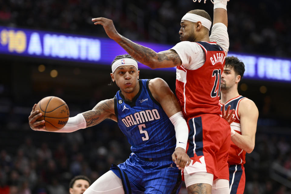 Orlando Magic forward Paolo Banchero (5) looks to pass the ball against Washington Wizards center Daniel Gafford (21) and forward Deni Avdija (9), right, during the second half of an NBA basketball game Friday, March 31, 2023, in Washington. The Magic won 116-109. (AP Photo/Nick Wass)