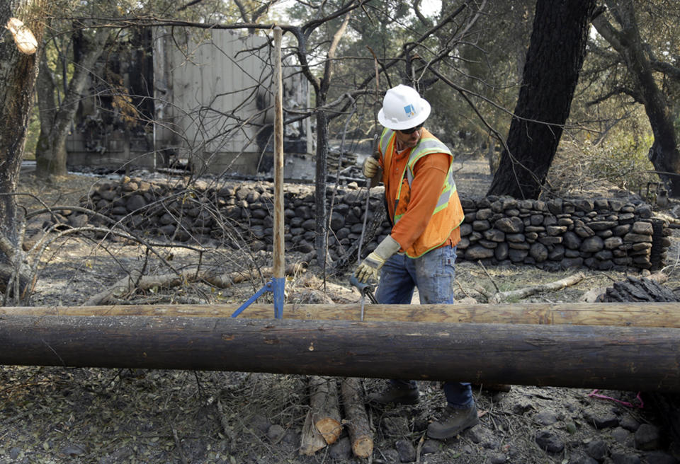 FILE - In this Oct. 18, 2017 file photo, a Pacific Gas & Electric worker replaces power poles destroyed by wildfires in Glen Ellen, Calif. Facing potentially colossal liabilities over deadly California wildfires, PG&E will file for bankruptcy protection. The announcement Monday, Jan. 14, 2019, follows the resignation of the power company's chief executive. (AP Photo/Ben Margot, file)