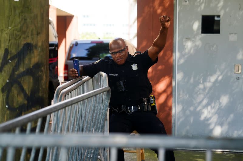 An Atlanta Police officer raises his fist as a rally against racial inequality and the police shooting death of Rayshard Brooks passes by, in Atlanta