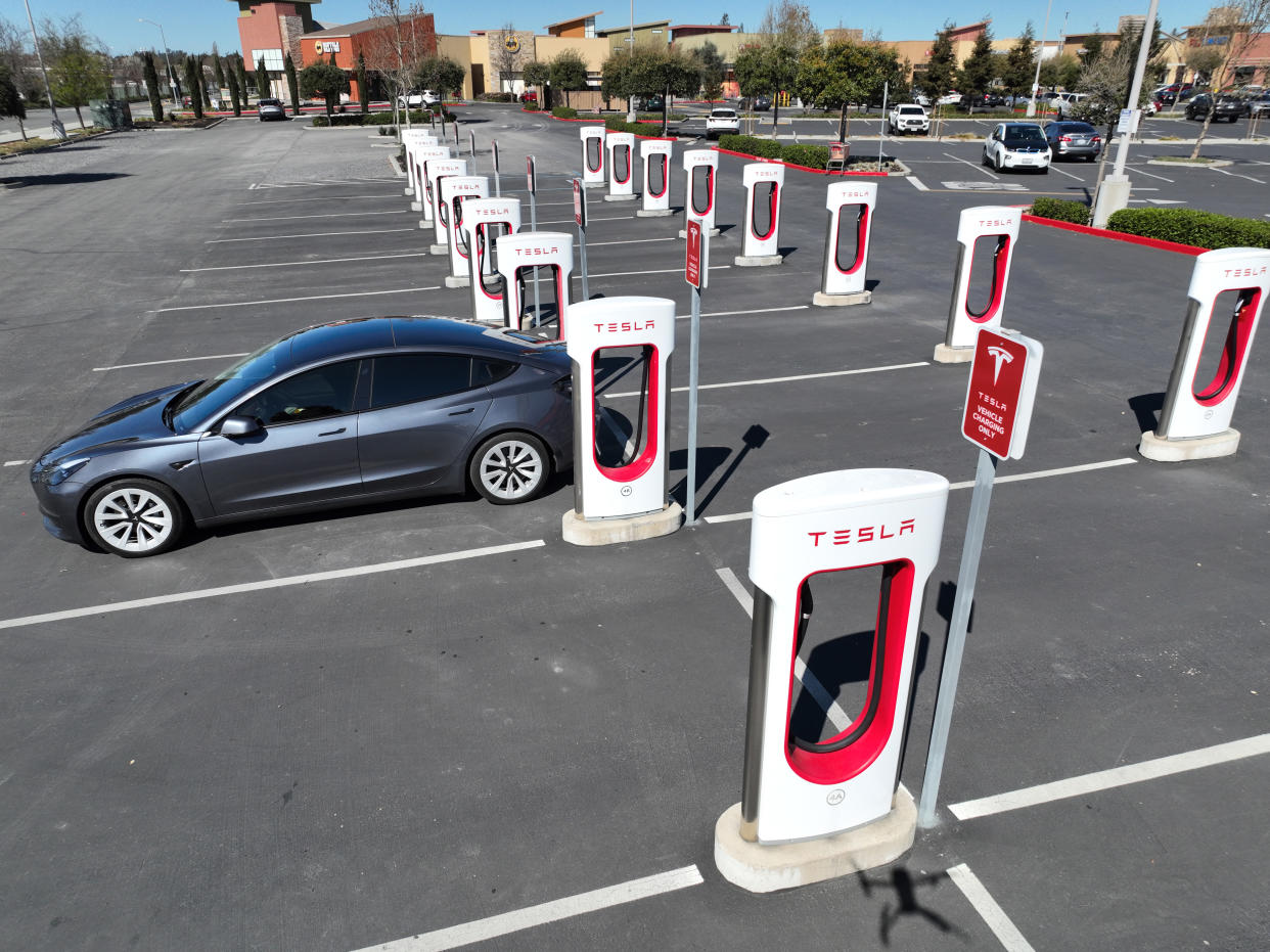 Tesla car recharges at a charging station, the only car for over a dozen available chargers.