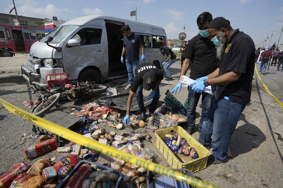 Pakistani investigators examine the site of a suicide attack in Karachi, Pakistan, Friday, April 19, 2024. A suicide bomber detonated his explosive-laden vest near a van carrying Japanese autoworkers, who narrowly escaped the attack Friday that wounded three bystanders in Pakistan's port city of Karachi, police said. (AP Photo/Fareed Khan)