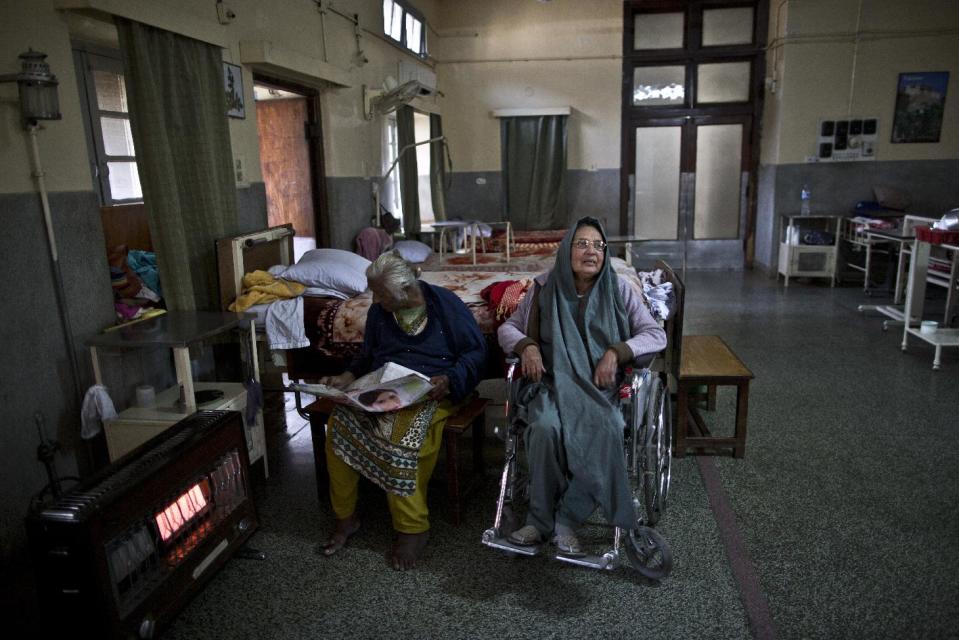 In this Saturday, Feb. 15, 2014, photo, Eldery Pakistani patients and residents at St. Joseph’s Hospice, from left, Ruth Robet, 60, reads the newspaper next to her roommate, Wazeera, 65, while sitting around the stove part of their morning routine, at the female ward of the hospice, in Rawalpindi, Pakistan. Mohammed Aqeel spent weeks at home in Pakistan waiting for death after suffering a debilitating spinal cord injury in a car crash before friends suggested he come to St. Joseph’s Hospice on the outskirts of the capital, Islamabad. Now 13 years later, his life and those of some 40 others who live on its grounds might be changed forever as this hospital of last resort faces closure over its rising debts. (AP Photo/Muhammed Muheisen)