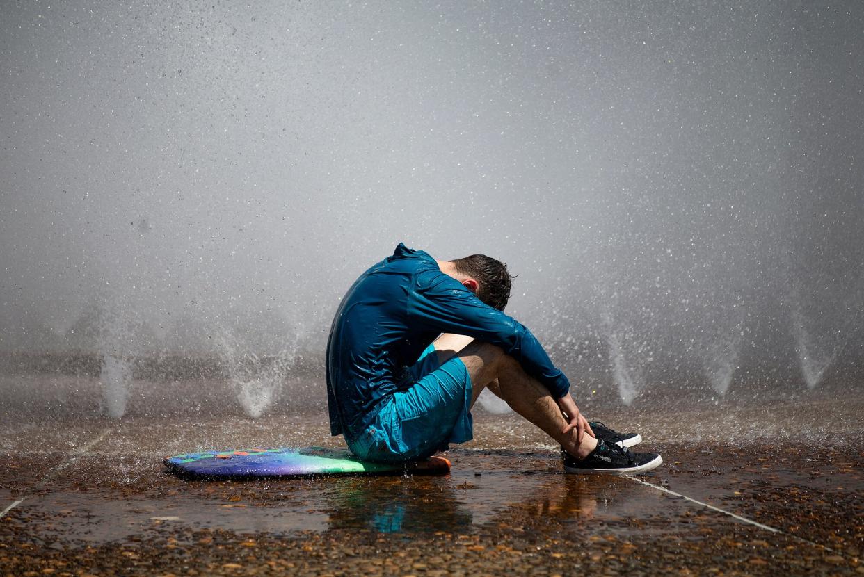 A man sits next to the Salmon Street Springs fountain in downtown Portland, Ore., on Tues., July 26, 2022. Temperatures were expected to reach triple digits as a heat wave that is forecast to last all week continued.