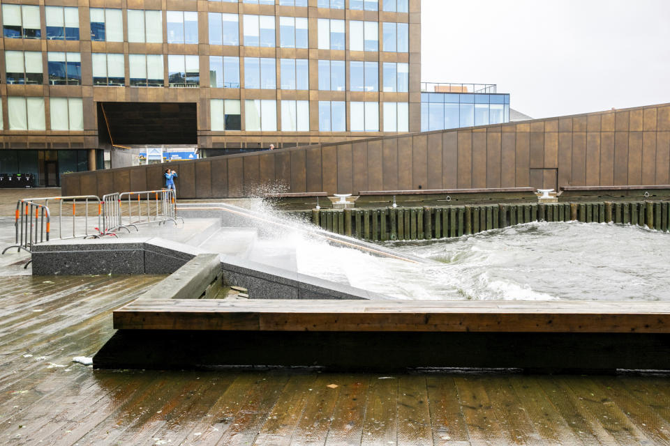 A woman takes a photograph of the crashing waves leading to the Halifax Harbor at the Queen's Marque public space in Halifax, Nova Scotia, on Saturday, Sept. 16, 2023. Severe conditions were predicted across parts of Massachusetts and Maine, and hurricane conditions could hit the Canadian provinces of New Brunswick and Nova Scotia, where the storm, Lee, downgraded early Saturday from hurricane to post-tropical cyclone, was expected to make landfall later in the day. (Kelly Clark /The Canadian Press via AP)