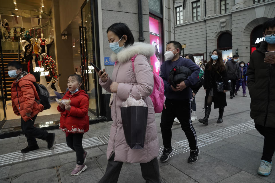 FILE - In this Jan. 14, 2021, file photo, residents, some wearing masks to protect themselves from the coronavirus, walk along a street in Wuhan in central China's Hubei province. A global team of researchers for the World Health Organization arrived Thursday in the Chinese city where the coronavirus pandemic was first detected to conduct a politically sensitive investigation into its origins amid uncertainty about whether Beijing might try to prevent embarrassing discoveries. (AP Photo/Ng Han Guan, File)