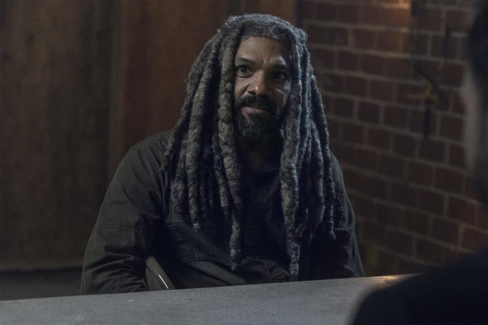 photo of Khary Payton as Ezekiel on The Walking Dead sitting at a table with brick wall behind him 