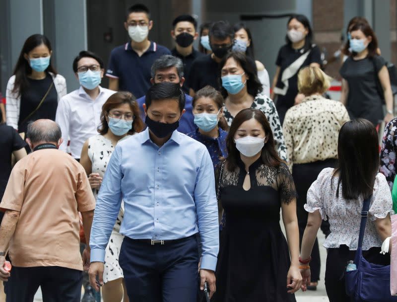 Office workers wearing masks cross a street during lunch hour, amid the coronavirus disease (COVID-19) outbreak, in Singapore