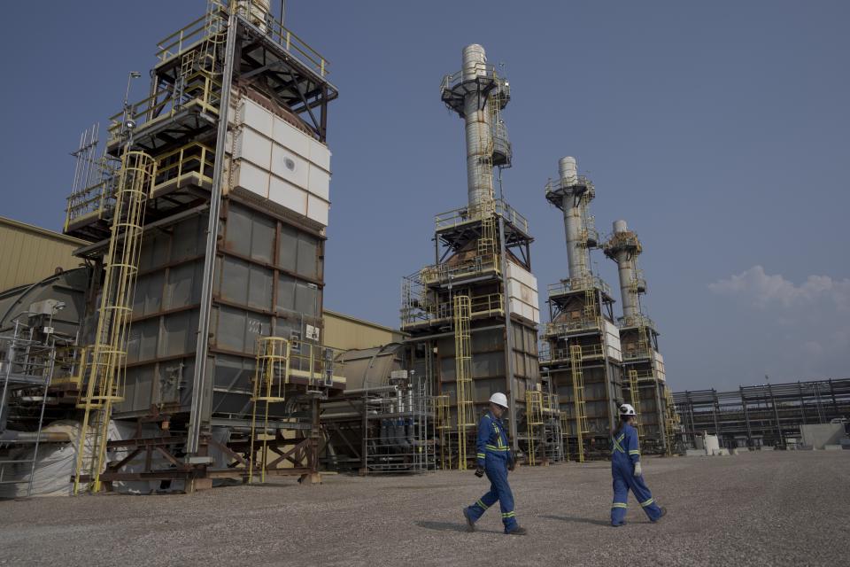 Carmen Lee Essington, vice president of Cenovus' oil sands operations, right, walks by steam-producing towers at Cenovus' Sunrise oil facility northeast of Fort McMurray on Thursday, Aug. 31, 2023. Essington said the company plans to extract all the oil below ground at their Sunrise plant. (AP Photo/Victor R. Caivano)