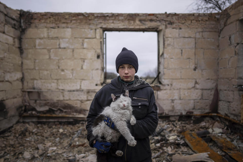 Danyk Rak, 12, holds a cat standing on the debris of his house destroyed by Russian forces' shelling in the outskirts of Chernihiv, Ukraine, Wednesday, April 13, 2022. After shelling Danyk's mother Liudmila Koval had to have her leg amputated and was injured in her abdominal cavity. She is still waiting for proper medical treatment. (AP Photo/Evgeniy Maloletka)