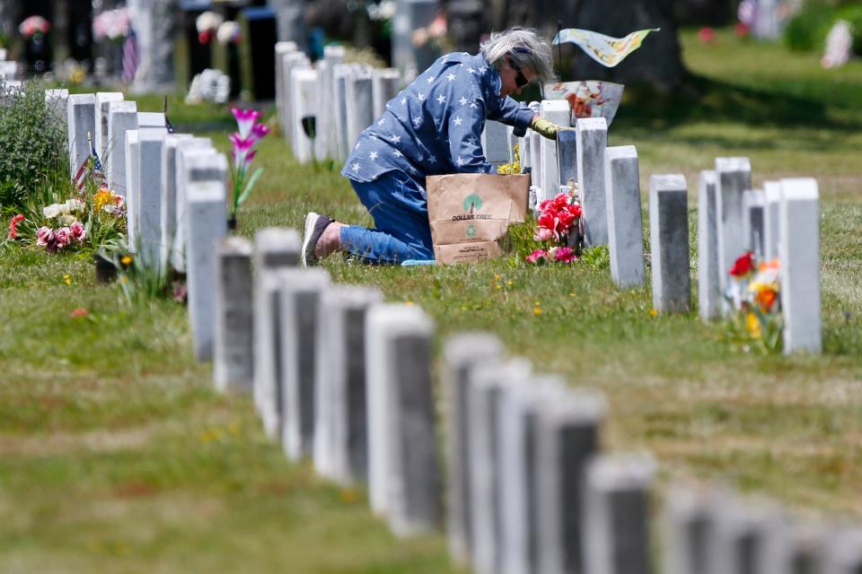 Diane Leclair installs flowers and American flags in front of her father Albert Charles Normandin's grave at Pine Grove Cemetery in New Bedford in preparation for Memorial Day. Mr. Normandin was a Marine during WWII and fought during the battle of Iwo Jima.