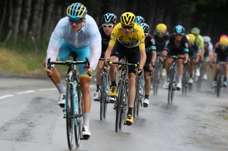 Britain's Chris Froome (3rd L), wearing the overall leader's yellow jersey, rides in the rain ahead of his teammate Geraint Thomas (2nd L) during the 146km 19th stage of the Tour de France cycling race, on July 22, 2016