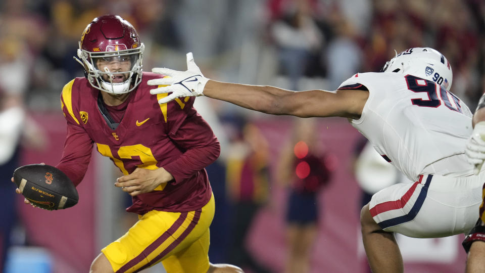 Southern California quarterback Caleb Williams, left, evades the tackle attempt by Arizona defensive lineman Isaiah Ward during the first half of an NCAA college football game Saturday, Oct. 7, 2023, in Los Angeles. (AP Photo/Marcio Jose Sanchez)