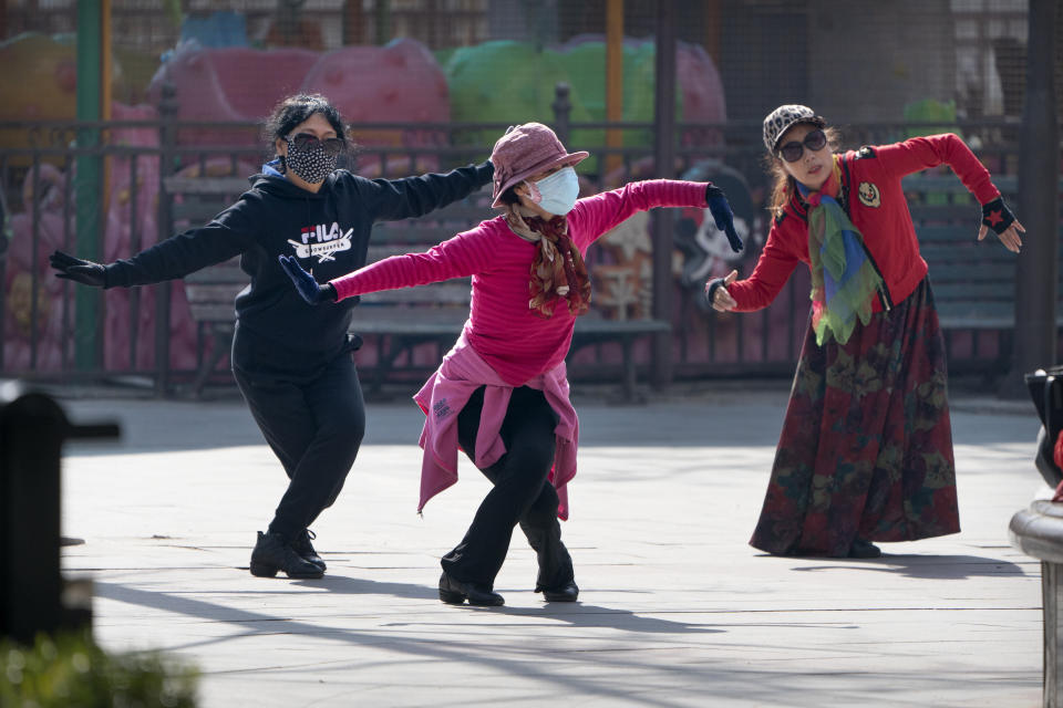 Women wearing face masks to protect against the spread of the coronavirus dance at a public park in Beijing, Friday, Feb. 19, 2021. China has been regularly reporting no locally transmitted cases of COVID-19 as it works to maintain control of the pandemic within its borders. (AP Photo/Mark Schiefelbein)
