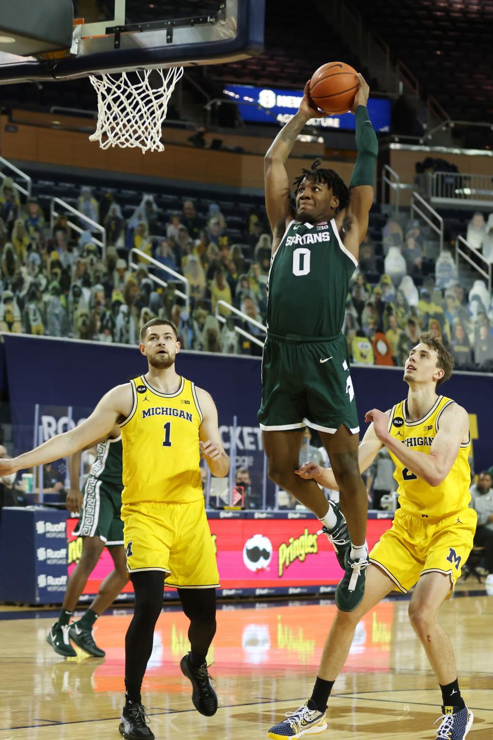 Michigan State's Aaron Henry dunks past Michigan's Hunter Dickinson (1) and Franz Wagner (21) during the first half at Crisler Center on March 4, 2021 in Ann Arbor.