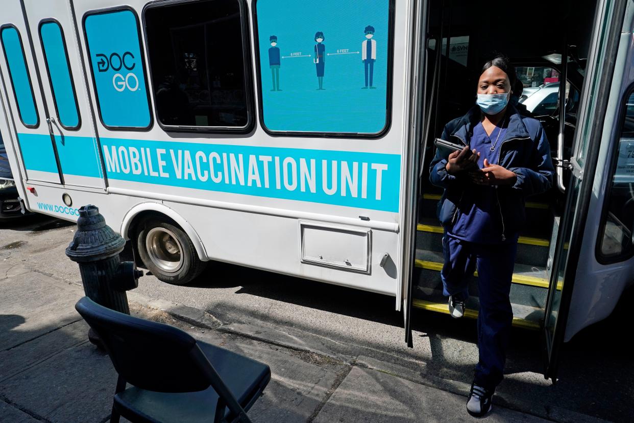 A health care worker steps out of a mobile vaccination van parked on a street corner in the Sunset Park neighborhood of Brooklyn, Monday, March 29, 2021, in New York. As part of New York City's ongoing efforts to increase access to the COVID-19 vaccine citywide, NYC Test & Trace Corps added mobile vaccination to its community vaccine clinic program Monday, launching this clinic-on-wheels with community partners Mixteca, a community organization serving Spanish-speaking and indigenous people in Brooklyn. The van is part of a pilot program. Officials say more vans will be announced as the program rolls out.