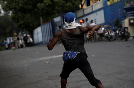 A protester throws a rock towards Haitian National Police (PNH) officers during clashes at a demonstration called by artists to demand the resignation of Haitian president Jovenel Moise, in the streets of Petion Ville, Port-au-Prince