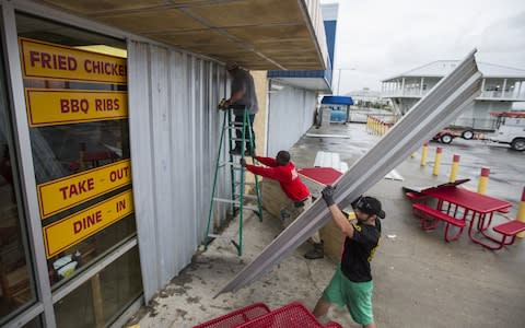 Charles Jackson, front, Immanuel Hubbard, center and Rober Butler board up Mother Cluckers at the Pass Christian Port Harbor Marina as Hurricane Nate approaches the northern Mississippi Gulf Coast - Credit: Getty