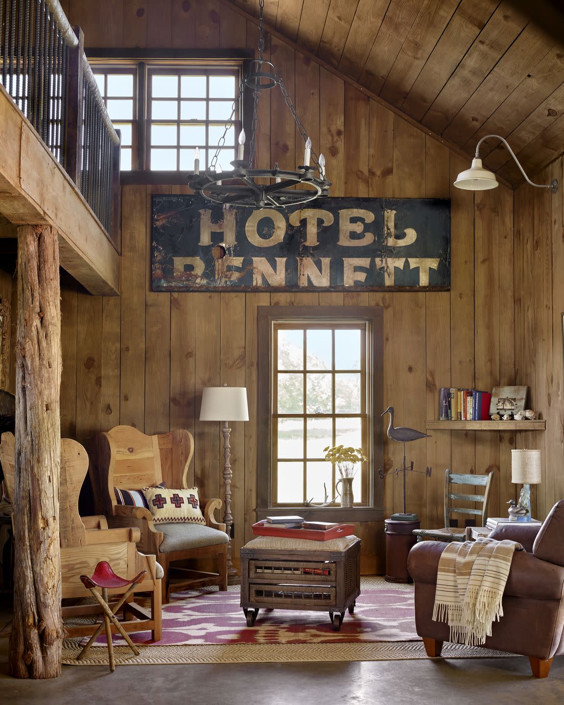 barn living room with leather chair, wooden wing backs, and large vintage sign