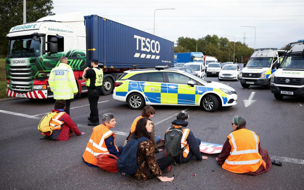 Insulate Britain activists with their hands glued to the ground block a roundabout at a junction on the M25 motorway during a protest in Thurrock - HENRY NICHOLLS/Reuters