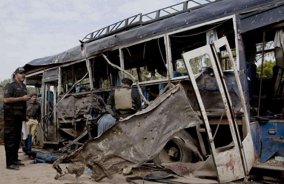 Pakistani police officers examine a damaged bus at the site of a bombing in Karachi, Pakistan, Thursday, Feb. 13, 2014. A bomb attack killed at least several police officers and wounded dozens others in Pakistan's southern city of Karachi on Thursday. (AP Photo/Shakil Adil)