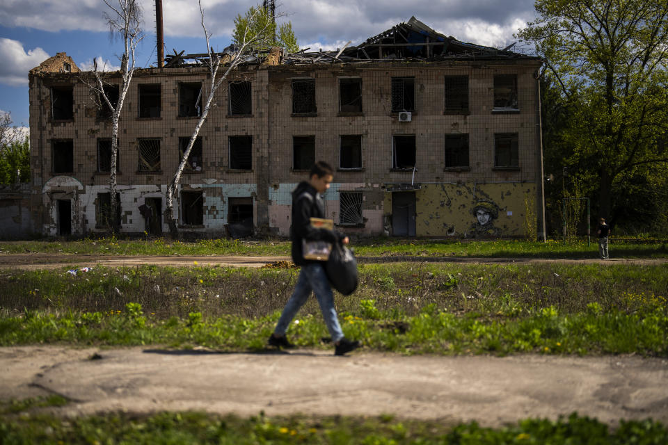 A young man walks past to partially destroyed building in Russian attacks in Borodyanka, north of Kyiv, Ukraine, Saturday, April 27, 2024. Borodyanka was occupied by Russian troops at the beginning of their full-scale invasion in 2022. (AP Photo/Francisco Seco)