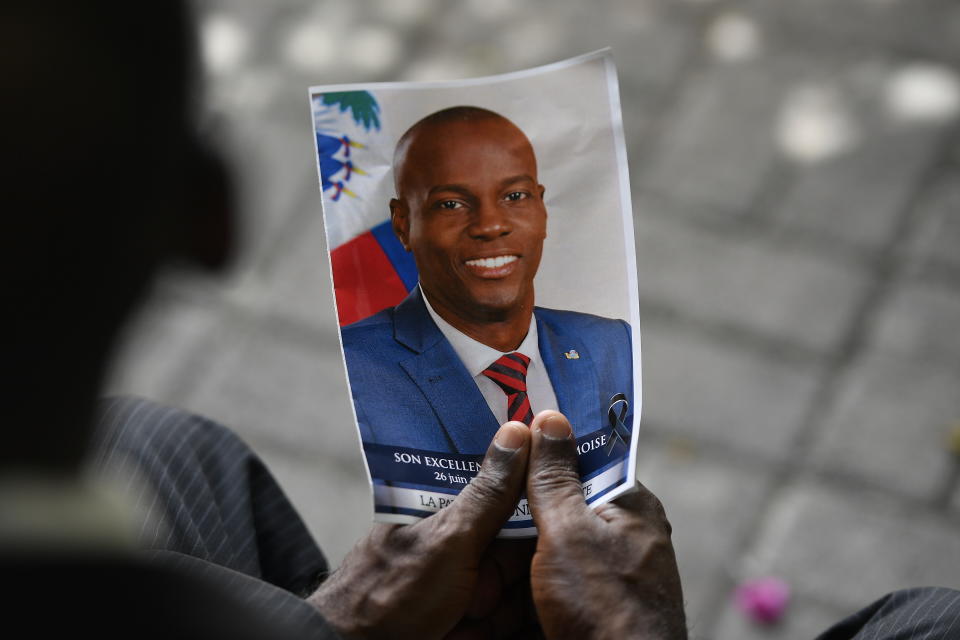 A person holds a photo of late Haitian President Jovenel Moise during his memorial ceremony at the National Pantheon Museum in Port-au-Prince, Haiti, Tuesday, July 20, 2021. Moise was assassinated at home on July 7. (AP Photo/Matias Delacroix)