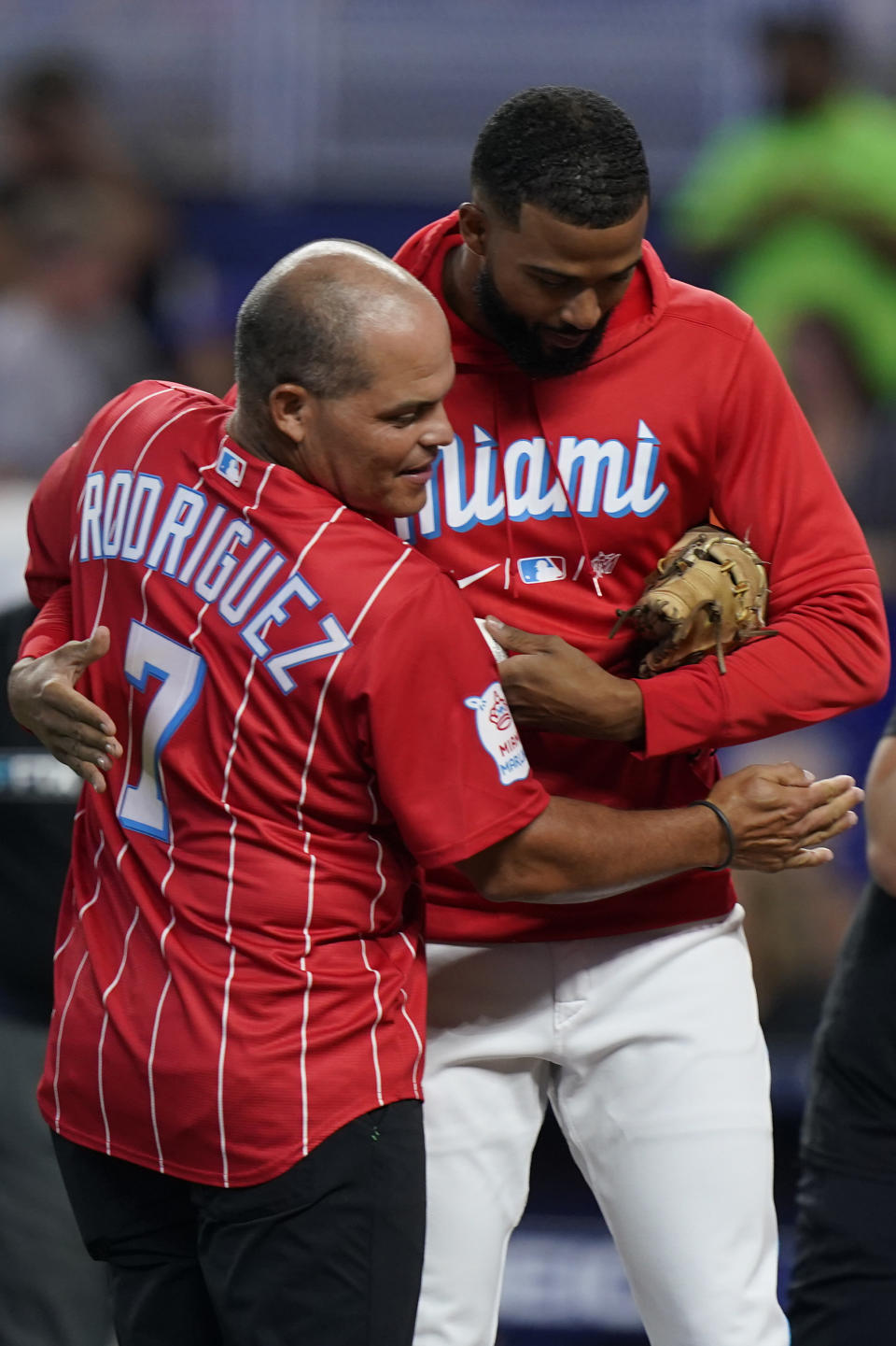 Baseball Hall of Famer Ivan "Pudge" Rodriguez, foreground, hugs Miami Marlins pitcher Sandy Alcantara after Rodriguez threw out a ceremonial first pitch before the start of a baseball game between the Marlins and the New York Mets, Saturday, July 30, 2022, in Miami. (AP Photo/Wilfredo Lee)