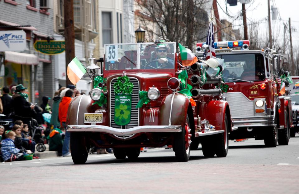 Antique fire trucks drive down Spring Street during Newton's St. Patrick's Day Parade on Saturday March 19, 2016.