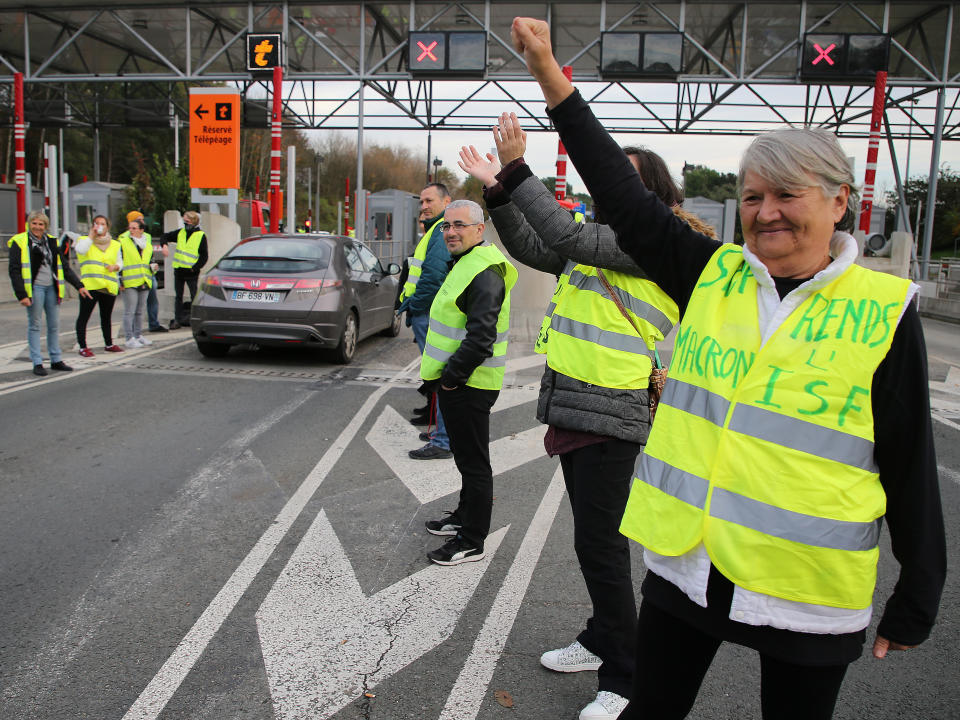 A demonstrator wearing a yellow jacket reading " Macron give us the wealth tax" protests at the toll gates on a motorway at Biarritz southwestern France, Wednesday, Dec.5, 2018.The concessions made by French president Emmanuel Macron's government in a bid to stop the huge and violent anti-government demonstrations seemed on Wednesday to have failed to convince protesters, with trade unions and disgruntled farmers now threatening to join the fray.(AP Photo/Bob Edme)