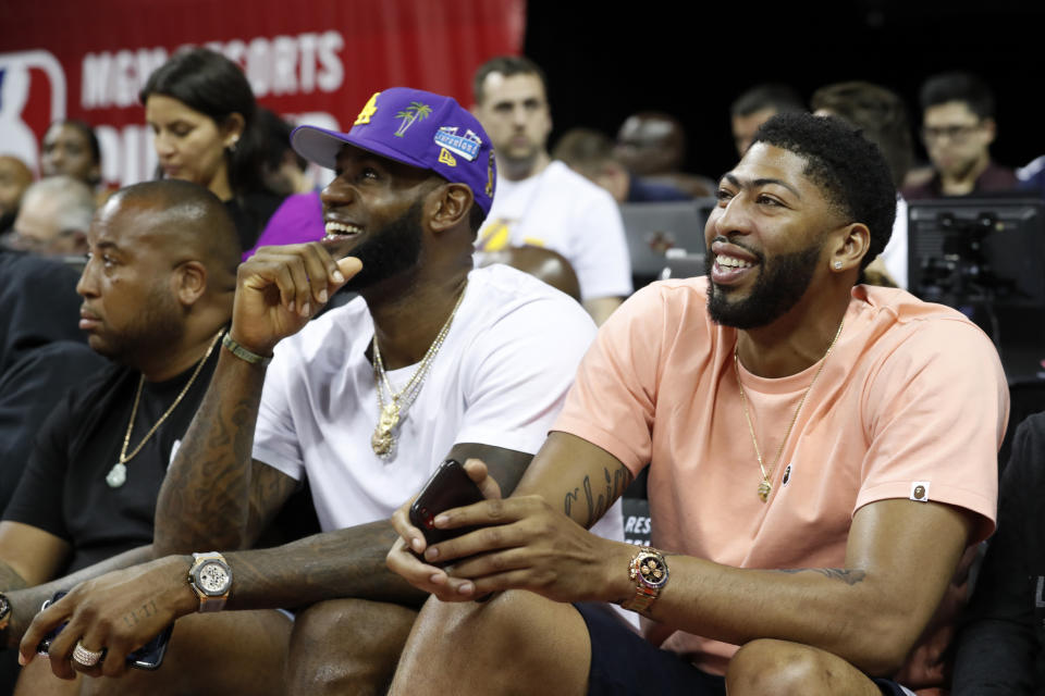Los Angeles Laker players LeBron James, center, and Anthony Davis, right, take in an NBA summer league basketball game between the New York Knicks and the New Orleans Pelicans, Friday, July 5, 2019, in Las Vegas. (AP Photo/Steve Marcus)