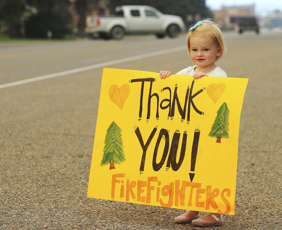 <p>Kylie Walter holds a sign as she and other kids wait for fire crews to return from fighting a wildfire near the ski town of Brian Head near the town of Panguitch, Utah, June 27, 2017. (Scott G Winterton/The Deseret News via AP) </p>