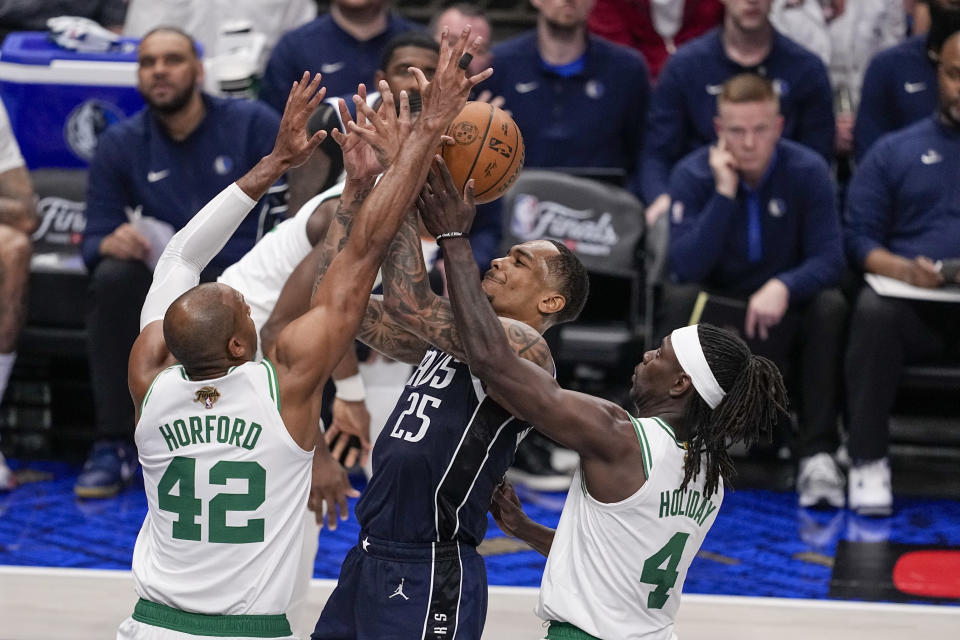 Dallas Mavericks forward P.J. Washington (25) goes up for a basket against Boston Celtics center Al Horford (42) and guard Jrue Holiday (4) during the first half in Game 3 of the NBA basketball finals, Wednesday, June 12, 2024, in Dallas. (AP Photo/Tony Gutierrez)